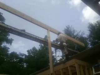 Carpenter setting a ridge beam over a new addition frame — Ice Dam Removal by Roofing Brothers in Saint Stephens Church
