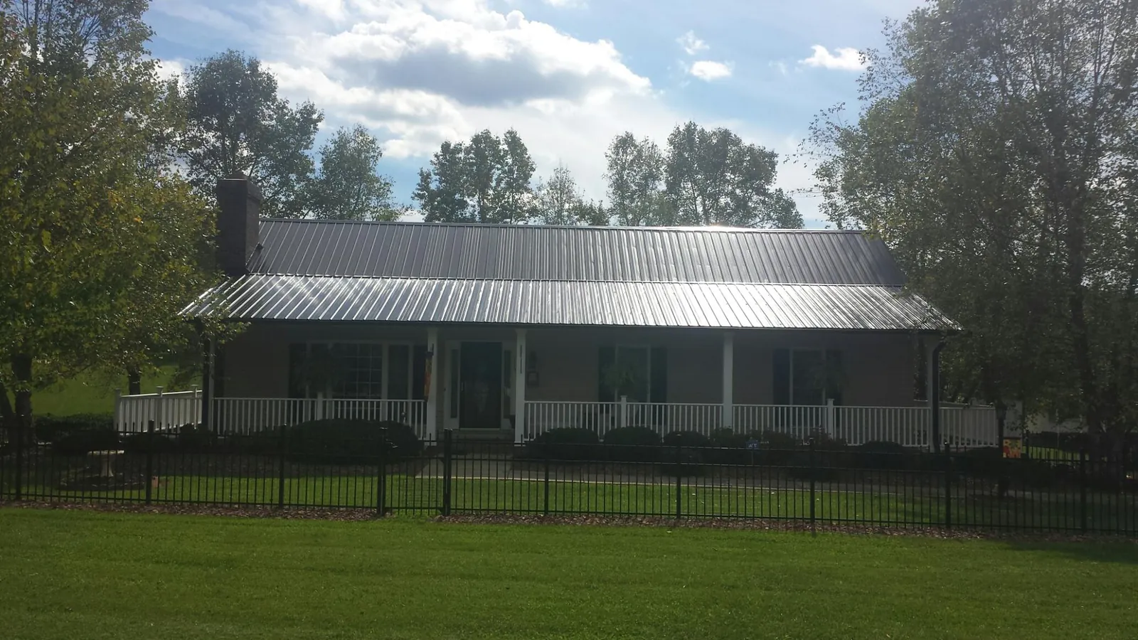 Gray metal roof on a brick ranch with a full width front porch — Gutter Guard Installation work by our crew in Saint Stephens Church