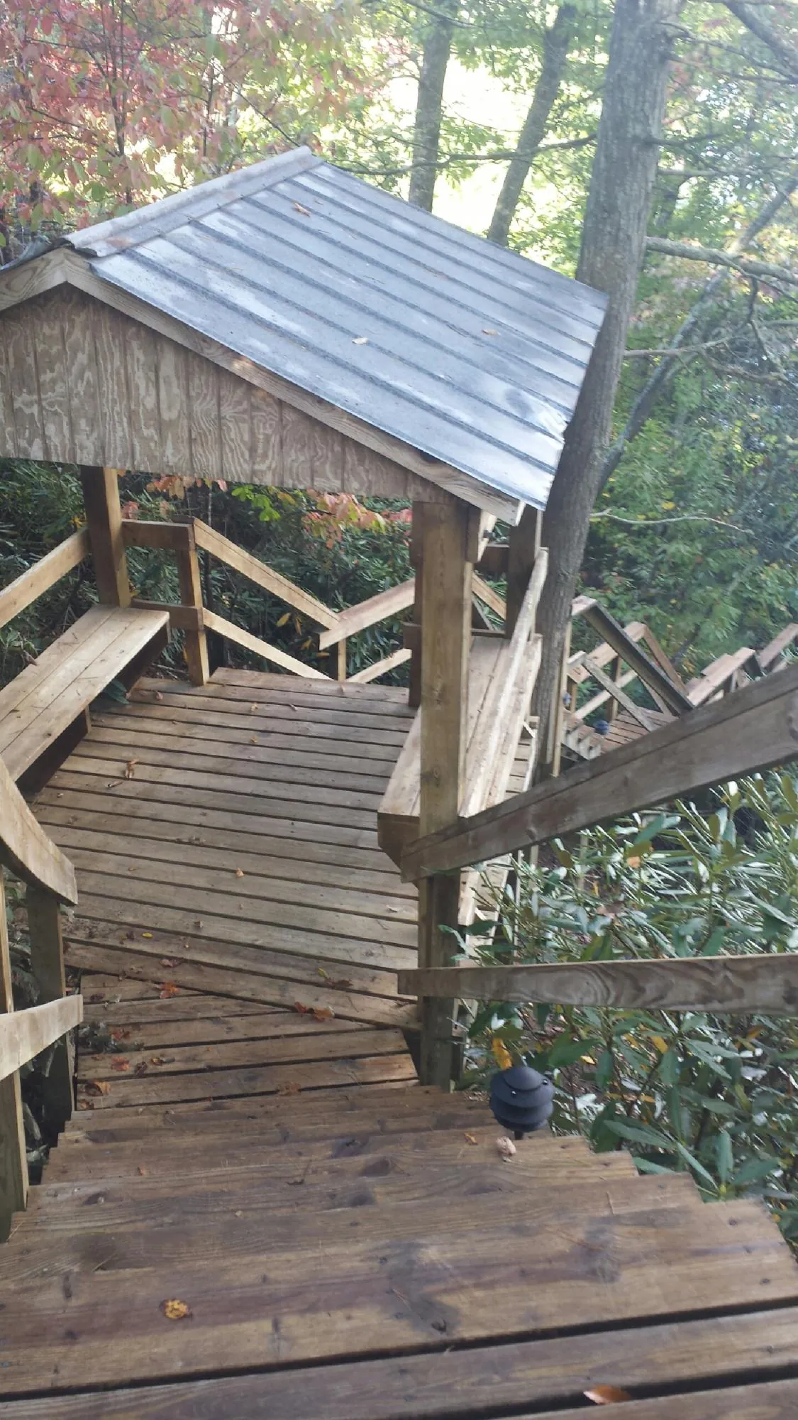Metal roofed shelter over wooden steps on a wooded walkway — Skylight Repair & Installation work by our crew in Saint Stephens Church