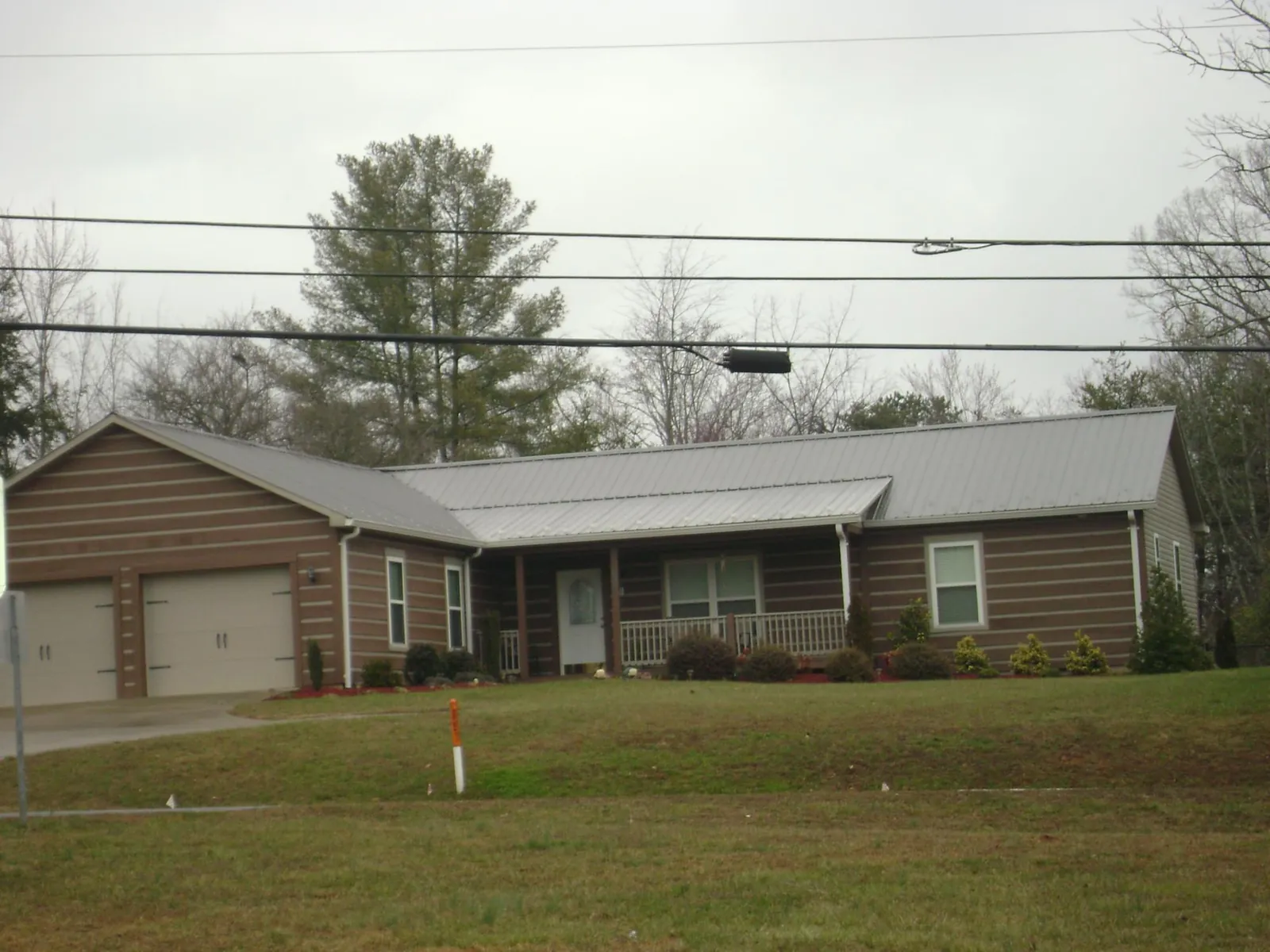 Gray metal roof on a log sided ranch home with a front porch in Saint Stephens Church