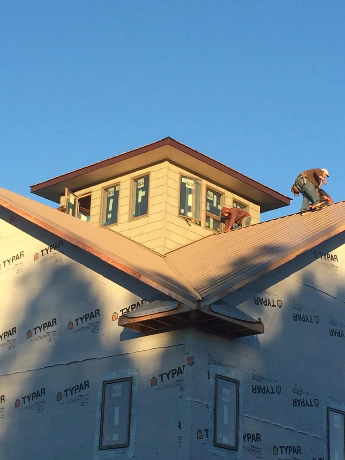 Roofers working around a rooftop cupola on a new metal roof at sunset — Roof Waterproofing in Saint Stephens Church by Roofing Brothers